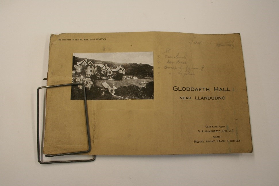 Clip papur enfawr yn dal Catalog Gwerthu Darluniadol o Neuadd Gloddaeth, Llandudno