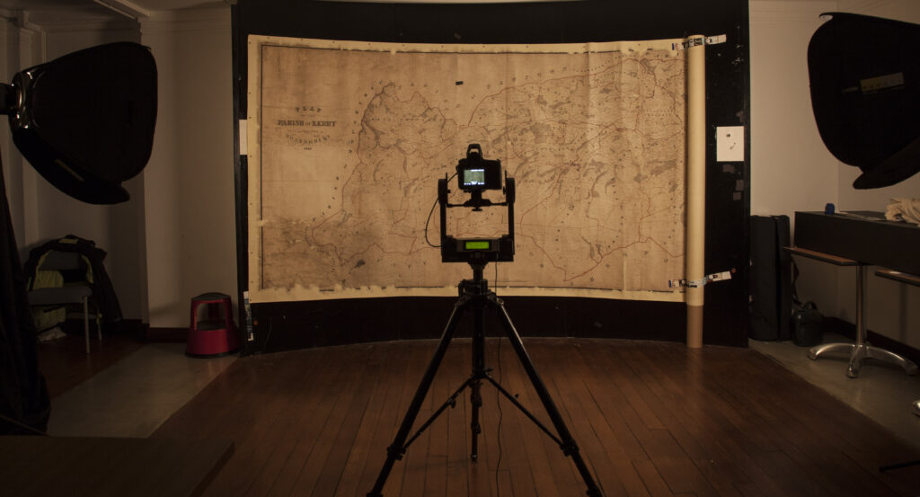 A large Tithe map is hung from a magnetic wall, with a digital camera set up in front of it.